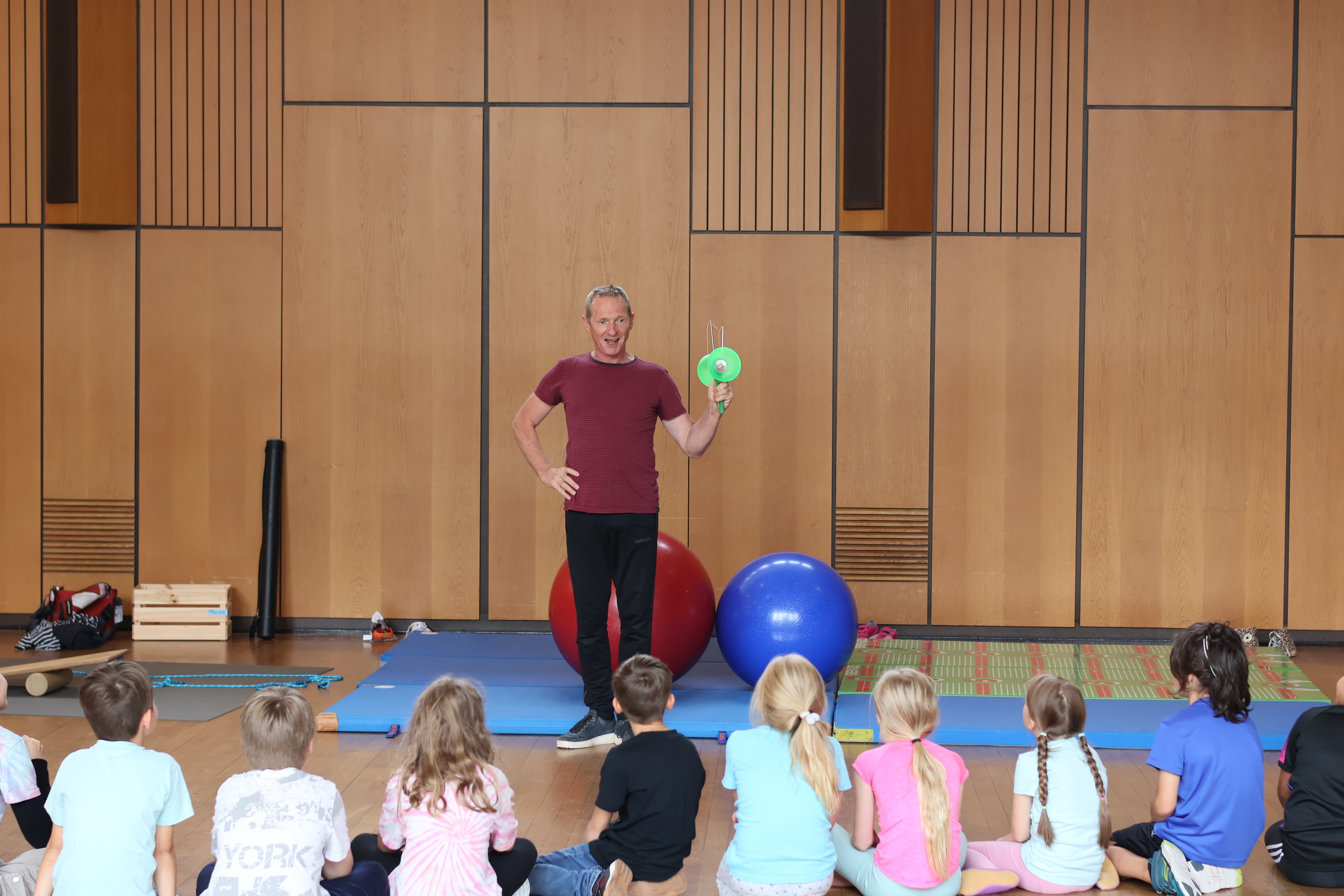 Zirkuspädagogik-Workshop: Kinder sitzen vor dem Jonglier-Trainer